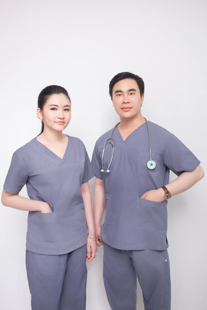 Male and female healthcare professionals in grey scrubs with a stethoscope.