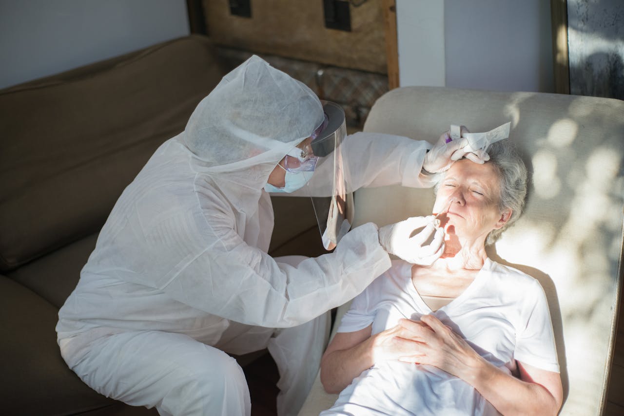 why-choose-us A healthcare professional in protective gear performs a COVID-19 test on a senior woman at home.